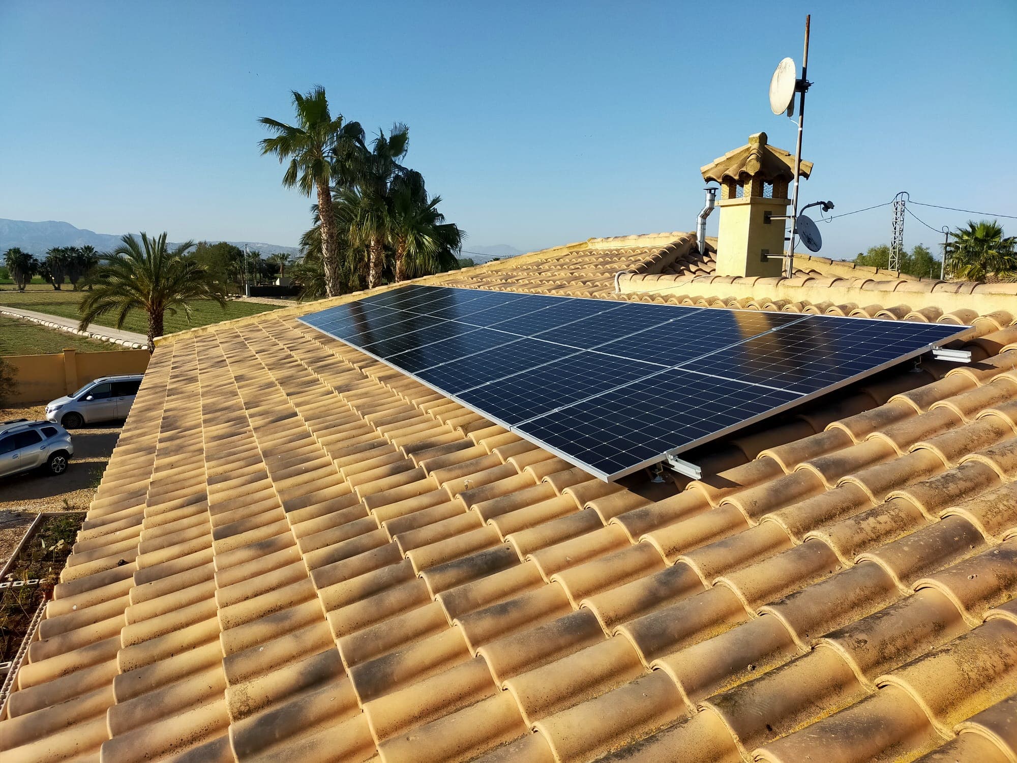 Solar panels on a tiled roof beside a chimney
