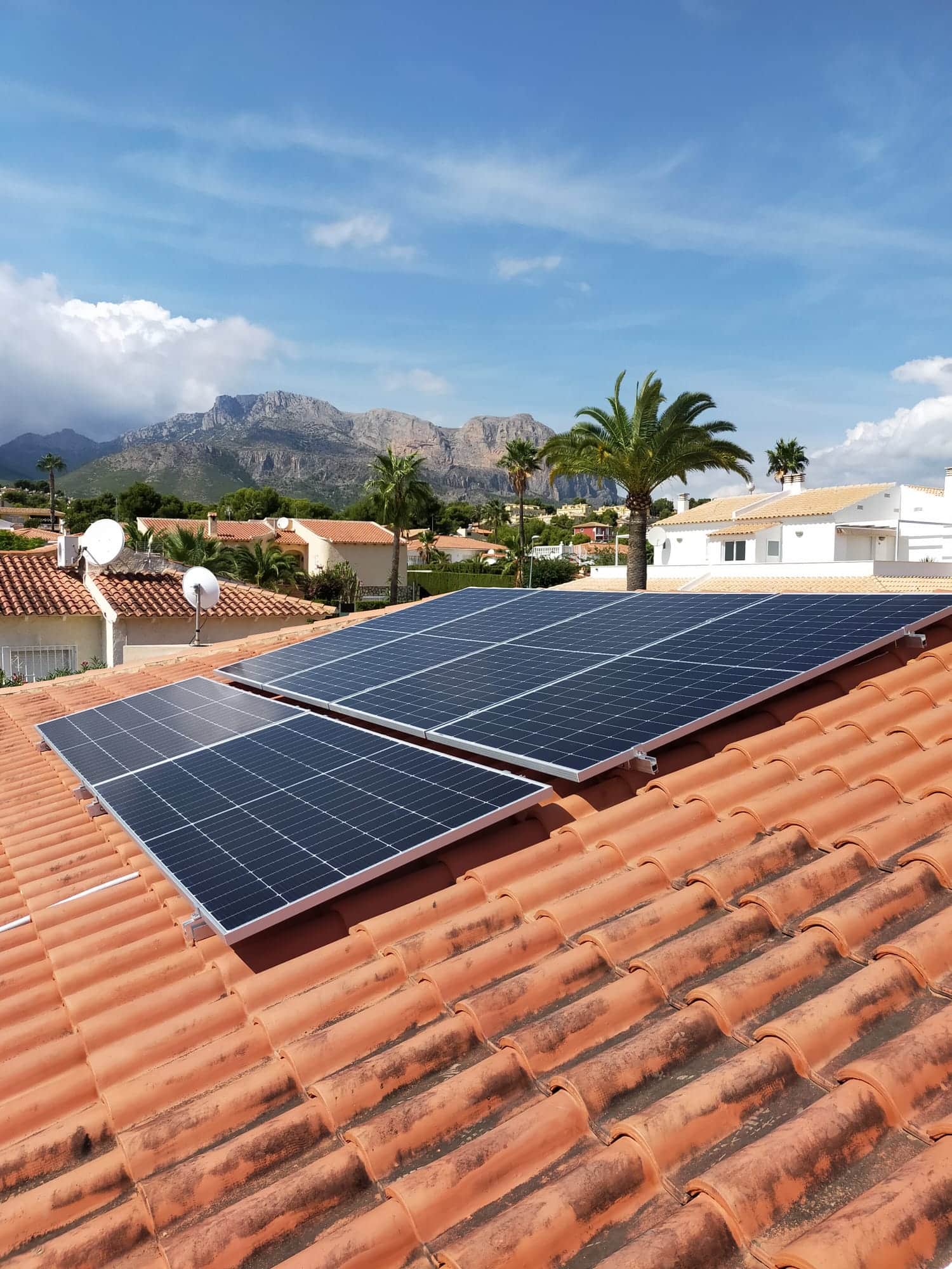 Solar panels on a tiled roof with the mountains behind